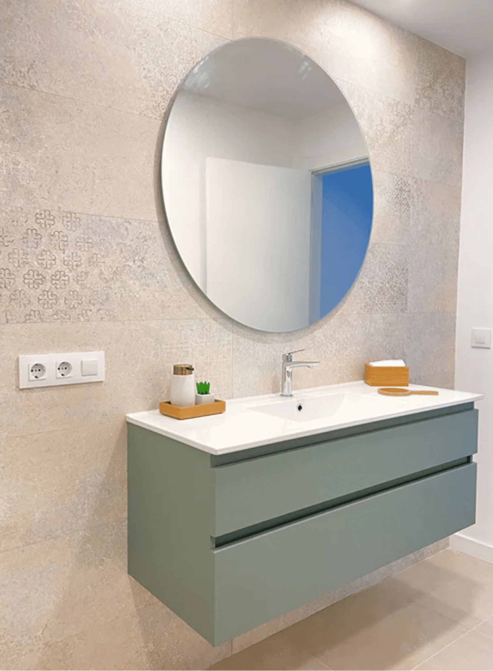 Mueble de baño suspendido en color verde menta con lavabo blanco y espejo redondo.