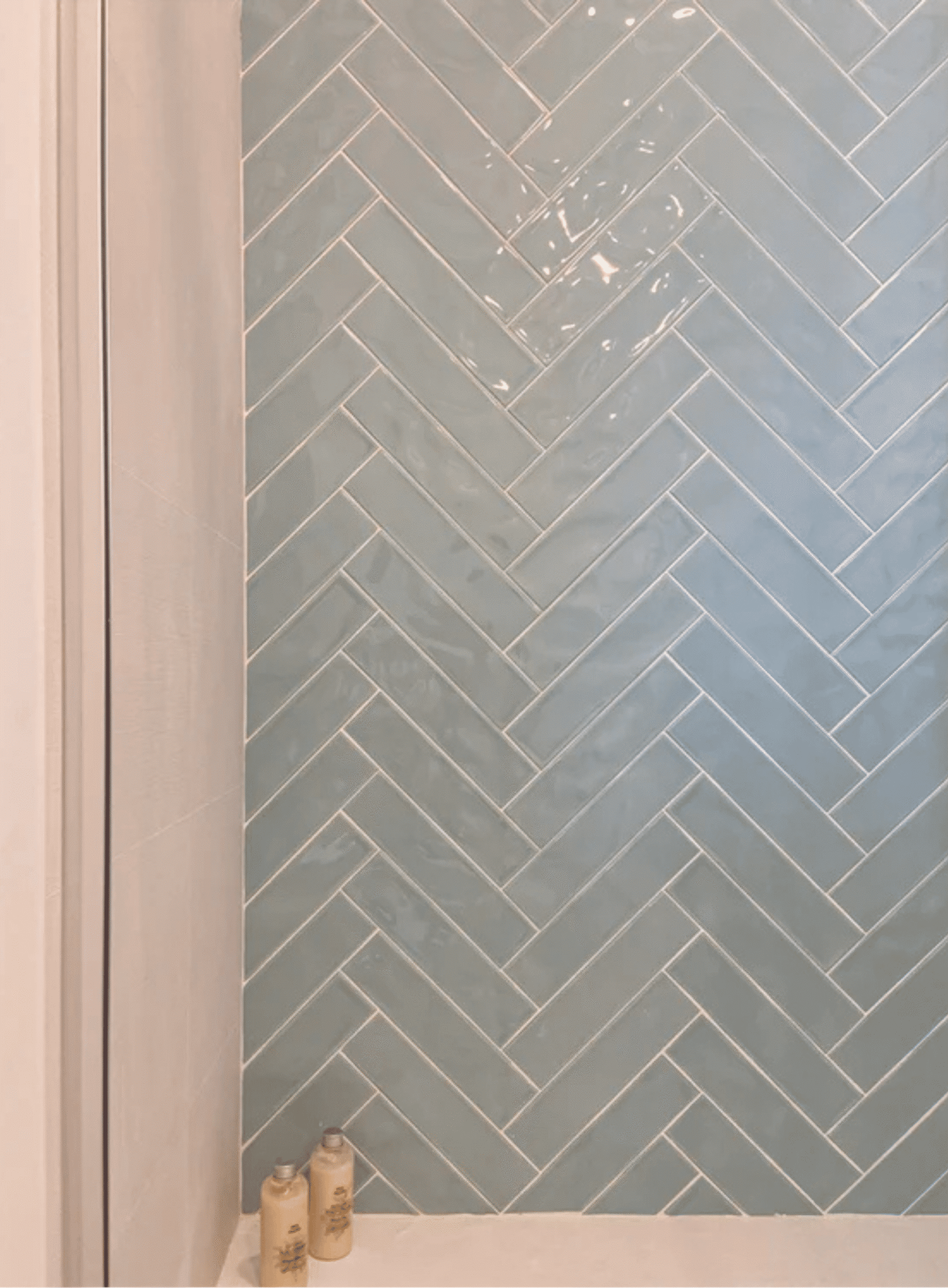 Baño moderno con mueble de madera, espejo circular y ducha con azulejos azul turquesa.