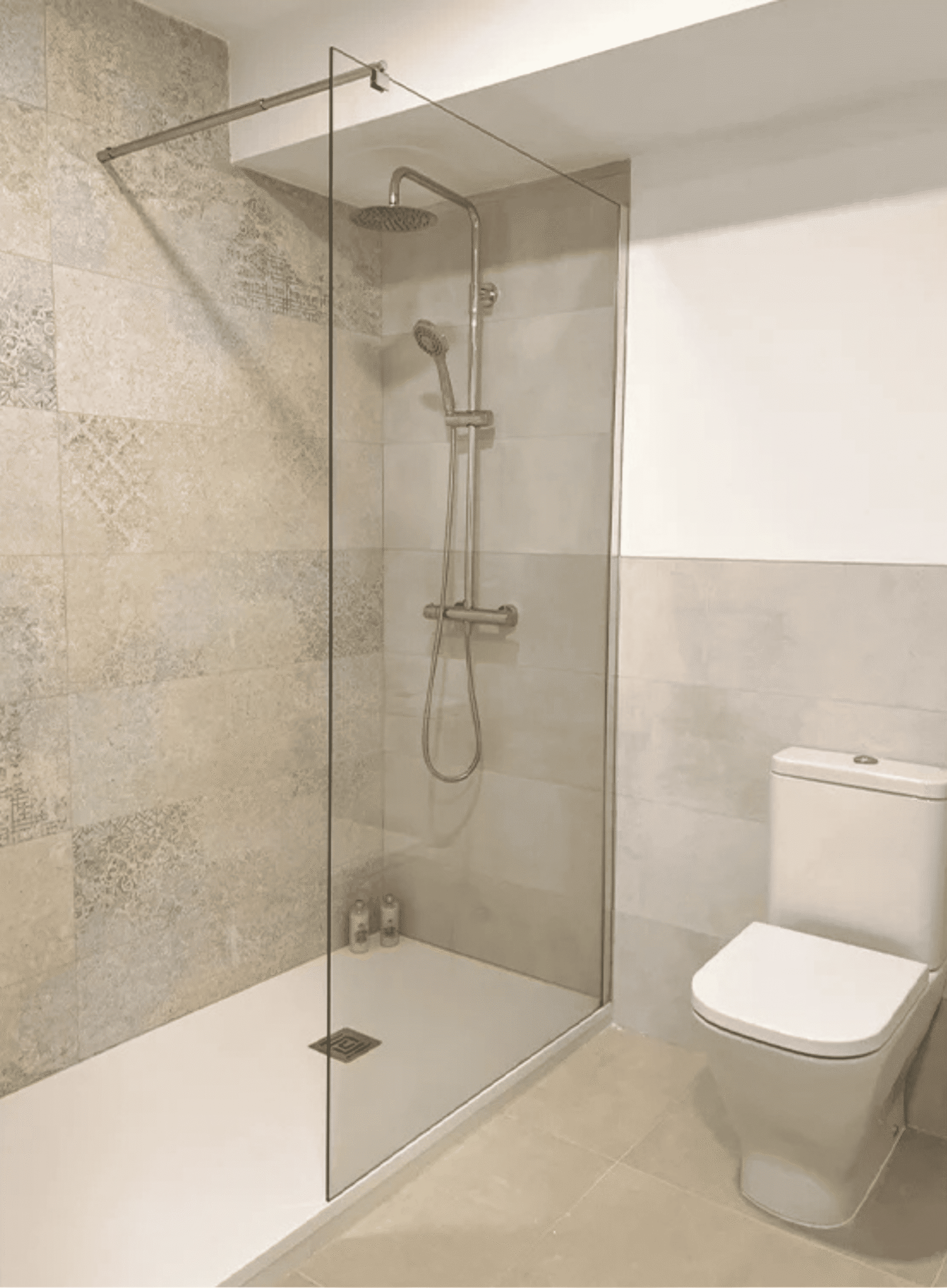 Plato de ducha blanco con mampara de cristal fija y grifería termostática cromada.