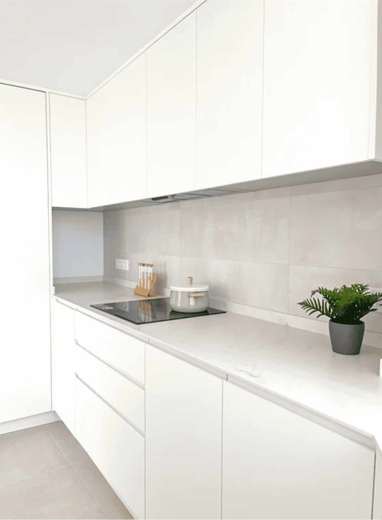 Encimera de cocina blanca con placa de inducción y muebles minimalistas sin tiradores.