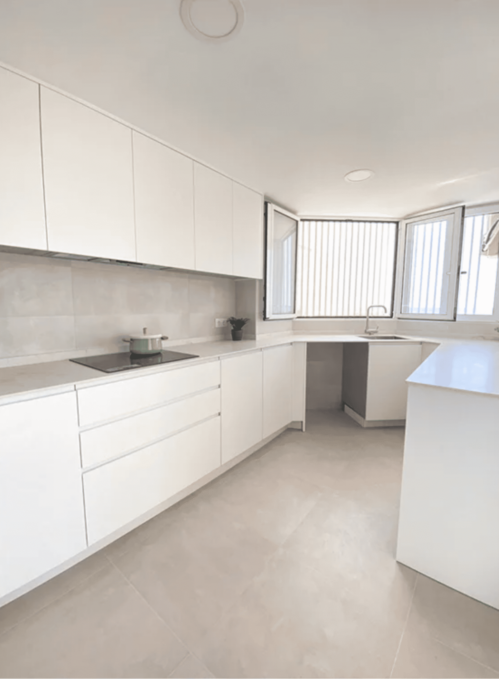 Encimera de cocina blanca con placa de inducción y muebles minimalistas sin tiradores.