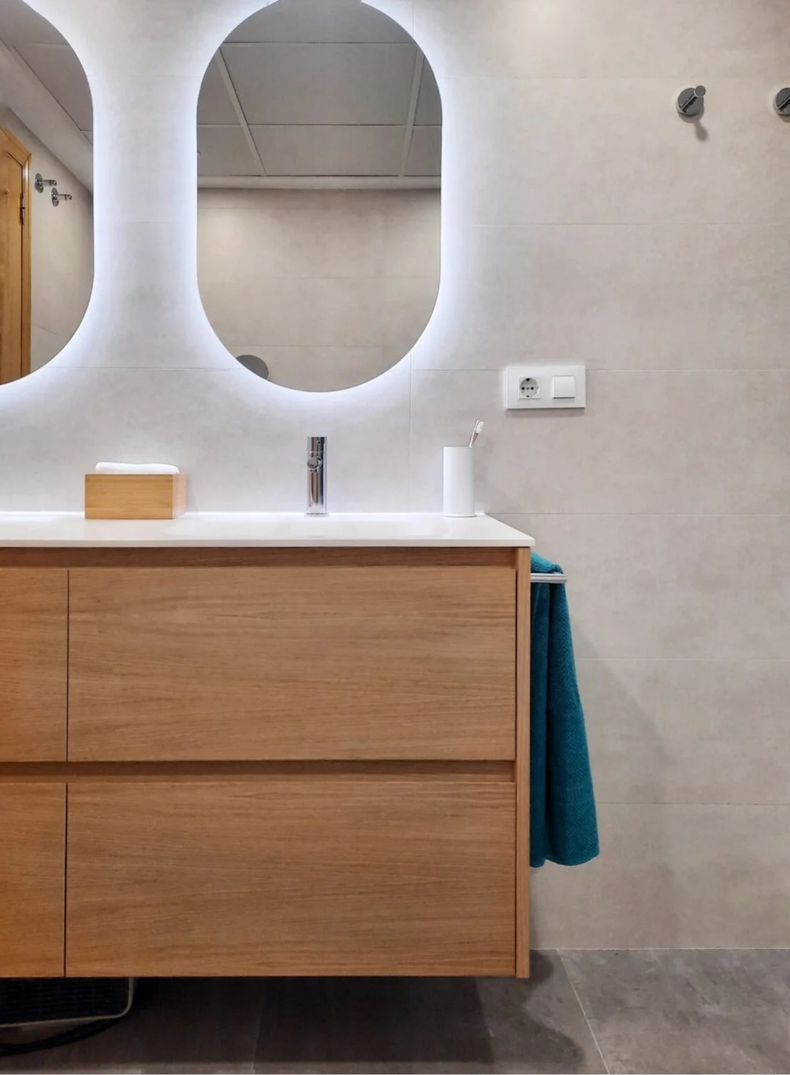 Mueble de baño de madera con doble cajón, lavabo blanco y espejo ovalado con luz LED.