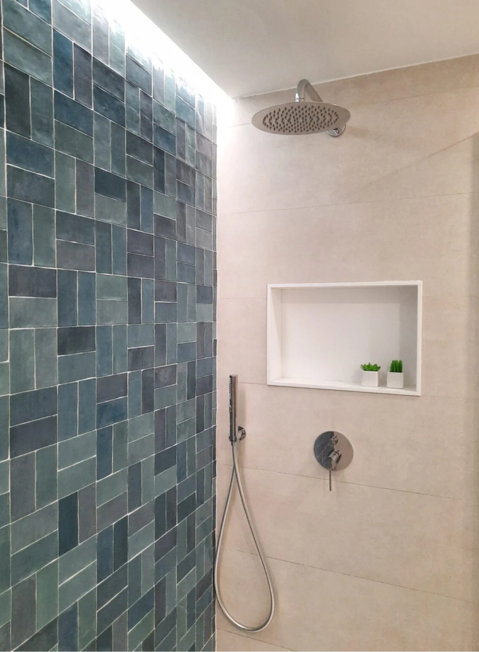 Zona de ducha con revestimiento de azulejos azules, rociador de techo y hornacina para geles.